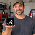 Model holding the Got Items Atlanta Braves black and white 3-inch square hitch cover; digital illustration.