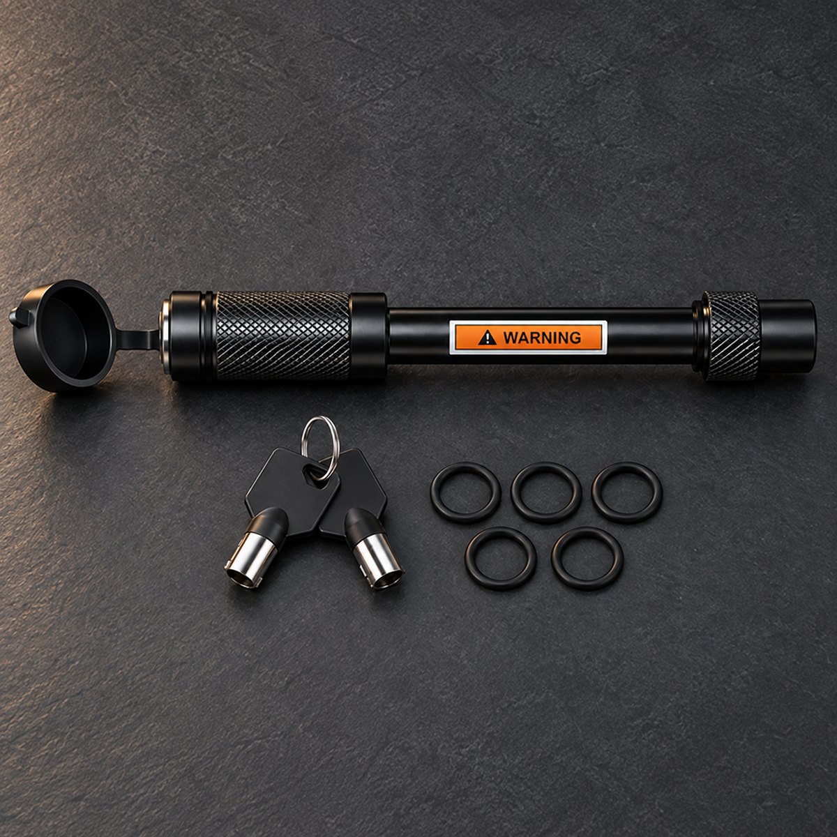 Black locking hitch pin with two tubular keys and five O-rings on a dark slate background